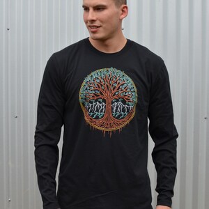 May include: A black long-sleeve shirt with a colorful tree of life design on the front. The tree is surrounded by a circle with a yellow outline.
