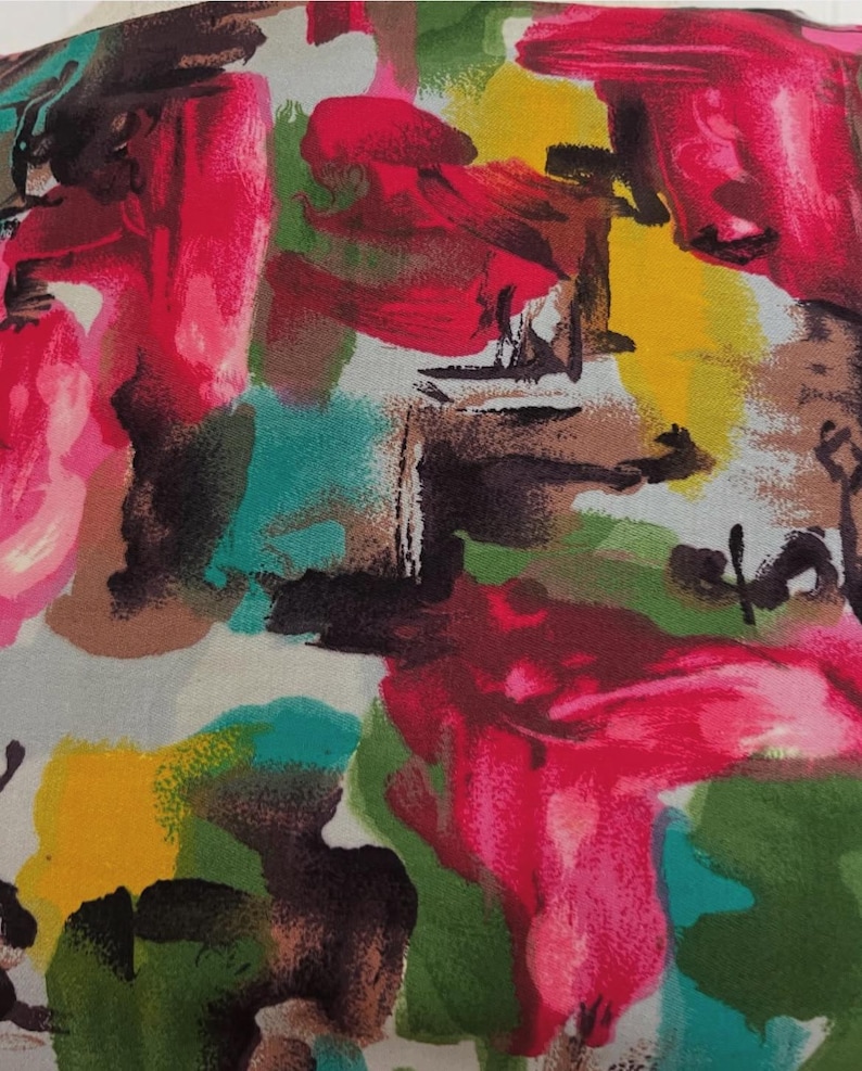 May include: Abstract fabric with a colorful design featuring shades of pink, yellow, green, teal, brown, and black. The fabric has a brushstroke pattern.