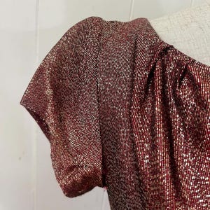 May include: A red and gold sparkly short-sleeved dress with a scoop neck.