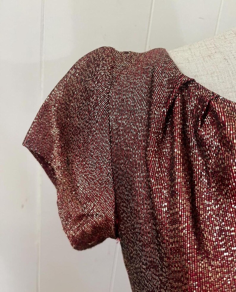 May include: A red and gold sparkly short-sleeved dress with a scoop neck.