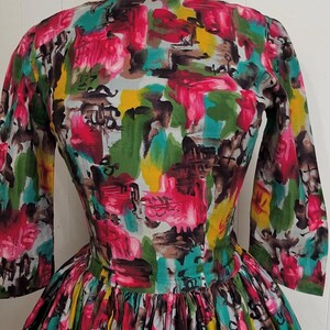 May include: A vintage dress with a colorful abstract print in shades of pink, green, yellow, and brown. The dress has a fitted bodice and a full skirt.
