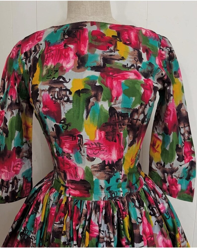 May include: A vintage dress with a colorful abstract print in shades of pink, green, yellow, and brown. The dress has a fitted bodice and a full skirt.