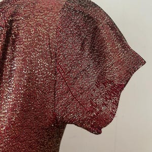 May include: A red and gold sparkly short-sleeved top with a scoop neck.