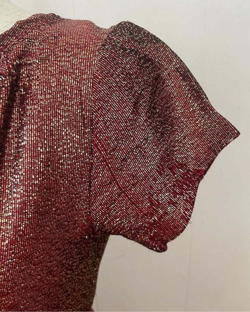 May include: A red and gold sparkly short-sleeved top with a scoop neck.