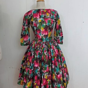 May include: A vintage dress with a colorful abstract print in shades of pink, green, yellow, and brown. The dress has a fitted bodice and a full skirt.