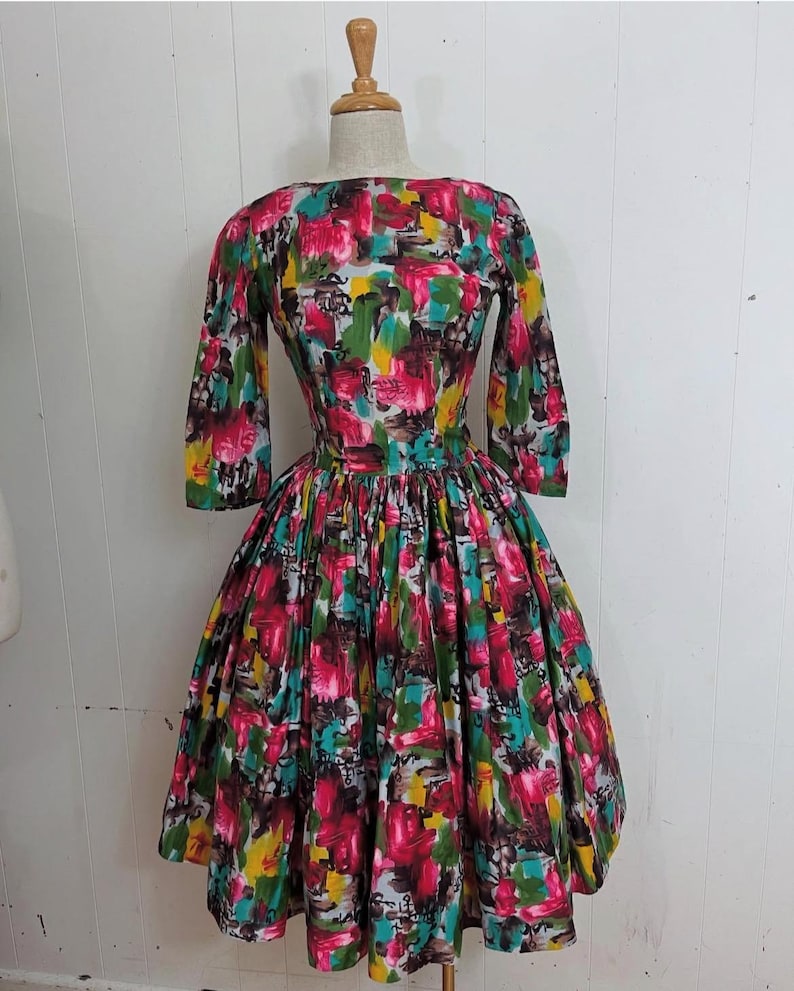 May include: A vintage dress with a colorful abstract print in shades of pink, green, yellow, and brown. The dress has a fitted bodice and a full skirt.