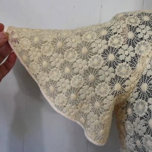 May include: A white lace top with a floral pattern. The sleeves are short and have a scalloped edge.