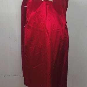 May include: A long, red coat with a satin lining. The coat is displayed on a mannequin. The interior lining is a bright red color. A tag inside the coat reads "FURCHGOTTS".