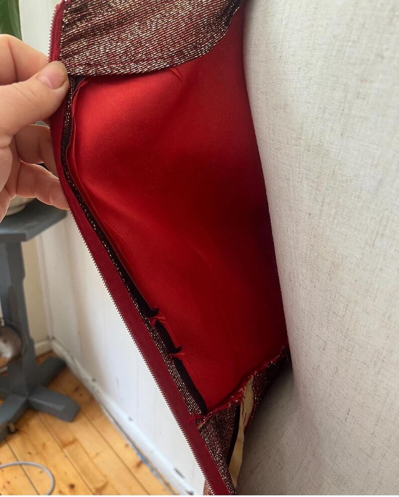 May include: A red and gold sequined dress with a zipper closure. The dress has a red lining and is shown on a white mannequin.