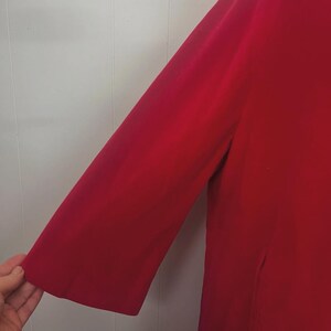 May include: A vibrant red coat with a three-quarter length sleeve. The coat is made of a smooth fabric and has a classic design. The sleeve is approximately 18 inches long.