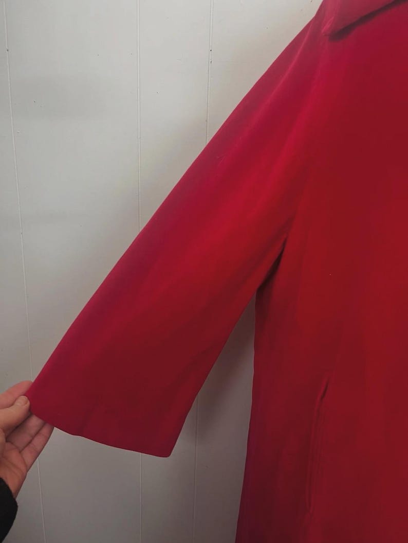 May include: A vibrant red coat with a three-quarter length sleeve. The coat is made of a smooth fabric and has a classic design. The sleeve is approximately 18 inches long.