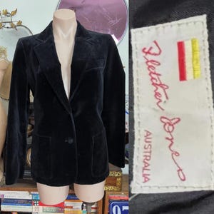 May include: A black velvet blazer with a notched lapel, two front pockets, and a single-button closure. The blazer is displayed on a mannequin. The label inside the blazer reads "Fletcher Jones AUSTRALIA".