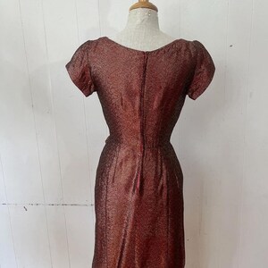 May include: A maroon sparkly dress with a scoop neck and short sleeves. The dress has a back zipper and a fitted silhouette.