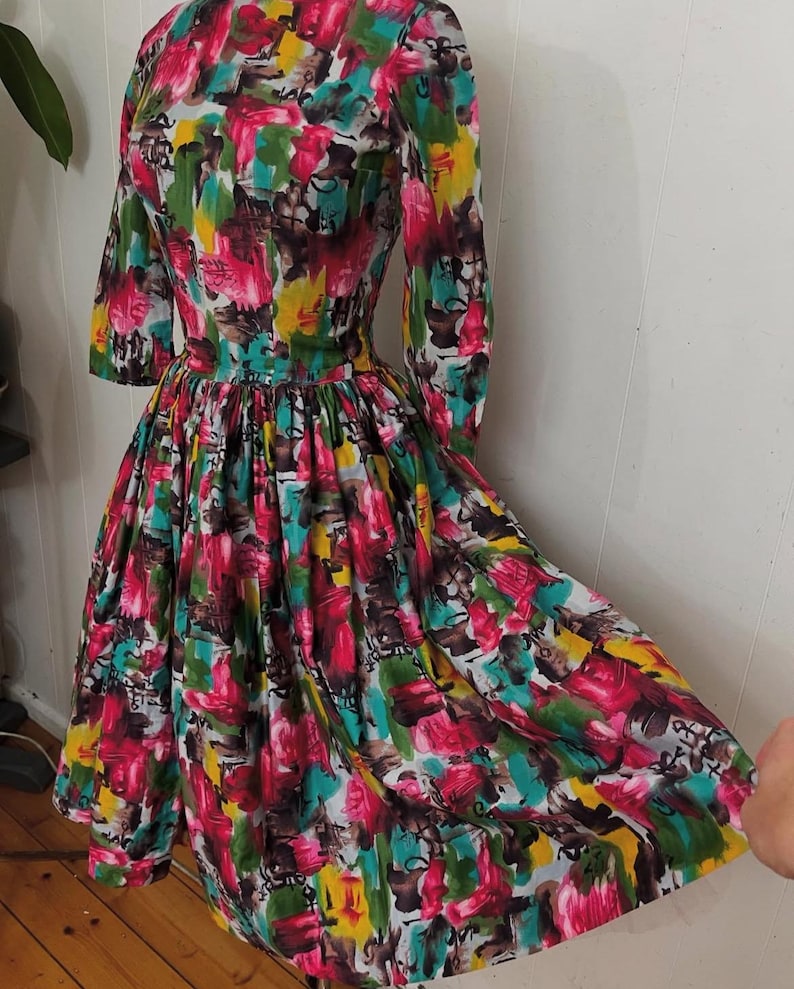 May include: A vintage dress with a colorful abstract print in shades of pink, green, yellow, and blue. The dress has a fitted bodice and a full skirt.