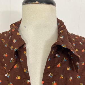 May include: A brown collared shirt with a small floral print in shades of blue, orange, white, and green.