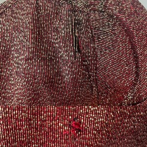 May include: Close-up of a red fabric with a subtle shimmer. The fabric is made of small, tightly woven threads, creating a textured surface.