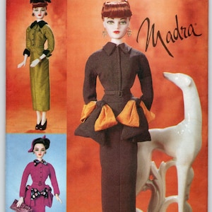 May include: Vogue Doll Collection pattern featuring a doll in a brown dress with orange accents. The pattern cover includes images of the doll in various outfits, including a pink suit and a green dress. The text "Madra" is written in cursive.