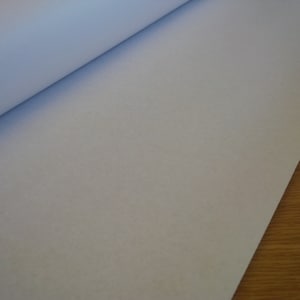 May include: A close-up of a white, smooth, and textured fabric. The fabric is rolled up and the edges are visible.