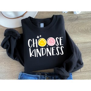 May include: Black sweatshirt with the text "CHOOSE KINDNESS" in white with two yellow and pink smiley faces.