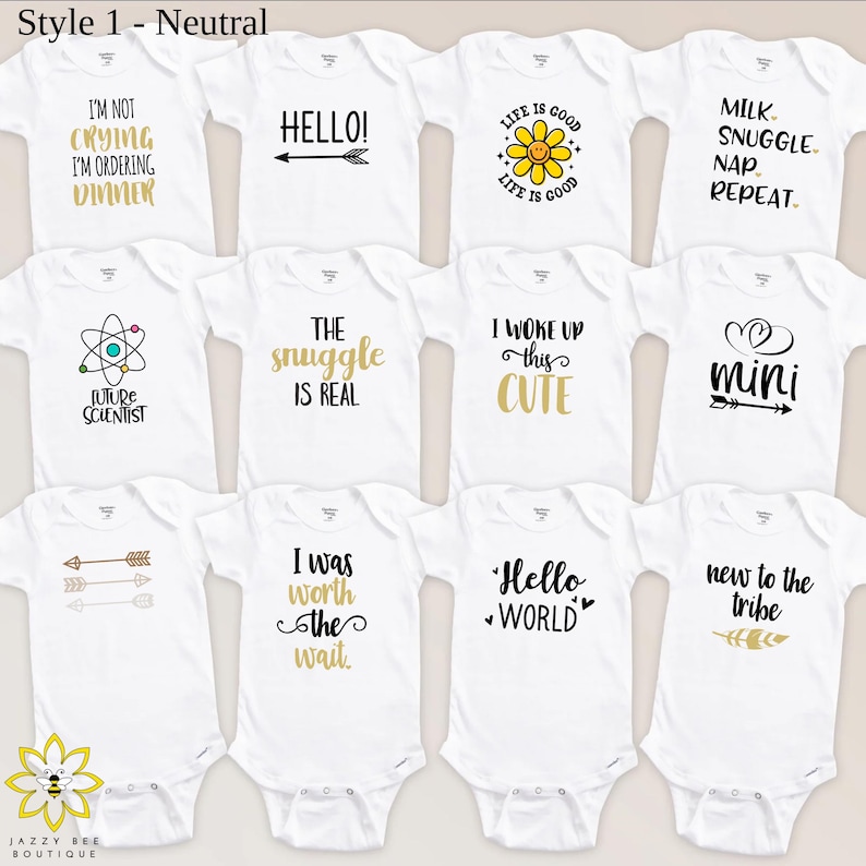 Pu&ograve; includere: Una collezione di body bianchi per neonati con vari disegni di testo neri e oro. Le frasi includono "I'm not crying, I'm ordering dinner", "Hello!" e "Life is Good". I body sono di Jazzy Bee Boutique.