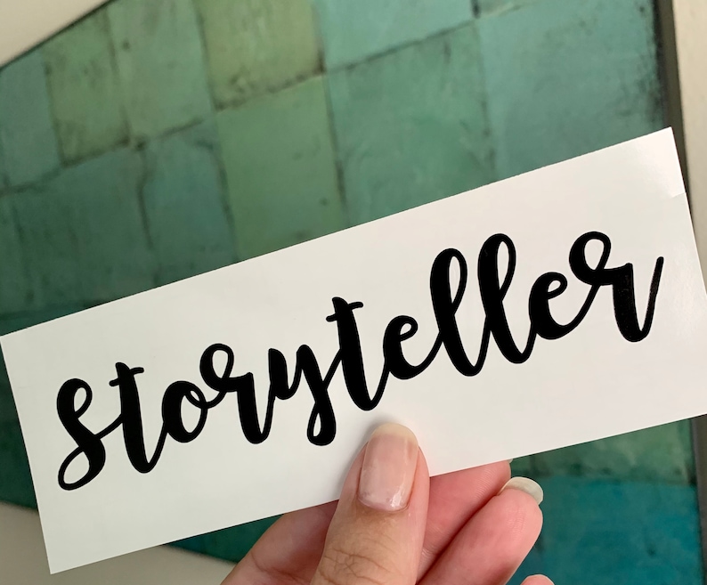 Pode incluir: Cart&atilde;o branco com a palavra "storyteller" escrita em caligrafia preta.