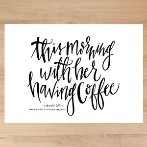 Può includere: Stampa tipografica in bianco e nero con la citazione "Questa mattina con lei a bere il caffè" attribuita a Johnny Cash. La citazione è scritta in un carattere corsivo.