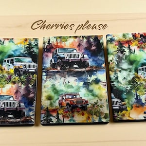 May include: Three decorative panels with watercolour paintings of off-road vehicles in a forest setting. The panels show various Jeeps and SUVs in vibrant colours. The text "Cherries please" is written in a cursive font at the top.