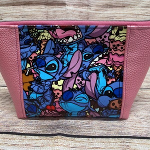 May include: A pink zippered pouch with a colourful print of Stitch characters from the Disney movie Lilo & Stitch. The print features Stitch in various poses and expressions, including a Stitch holding a drink.
