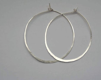 May include: A pair of silver hoop earrings with a hammered finish.