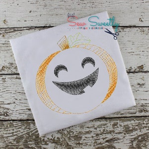 May include: A white fabric with a gold embroidered pumpkin with a black smiling face. The pumpkin has a green stem.
