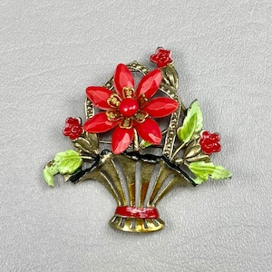May include: A vintage brooch featuring a red enamel flower with green enamel leaves in a gold-tone basket setting.