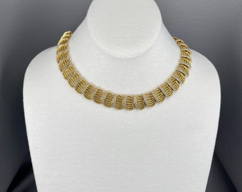 May include: A gold and silver necklace with a geometric design. The necklace is made of small, round beads that are arranged in a pattern of overlapping circles.