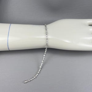 May include: A silver bracelet with small round clear stones set in a delicate chain.