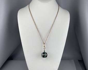 May include: A gold chain necklace with a black and green striped sphere pendant.