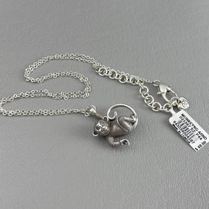 Peut inclure: Un collier argent&eacute; avec un pendentif singe. Le singe est d&eacute;taill&eacute; avec de la fourrure textur&eacute;e et est suspendu &agrave; un anneau. La cha&icirc;ne est d&eacute;licate et poss&egrave;de un fermoir mousqueton. Une &eacute;tiquette avec le texte "MONKEYNG ARND" est attach&eacute;e.