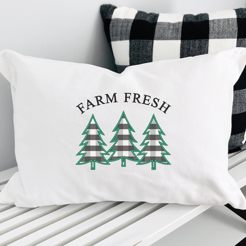 May include: White pillow with the text "FARM FRESH" in black lettering and three green and black checkered trees.