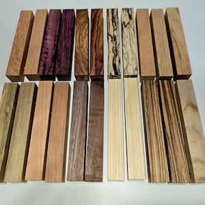May include: A collection of rectangular wooden blocks in various shades of brown, purple, and cream. The wood grains and textures vary, showcasing natural patterns. The blocks are arranged neatly, suggesting a craft or woodworking project.