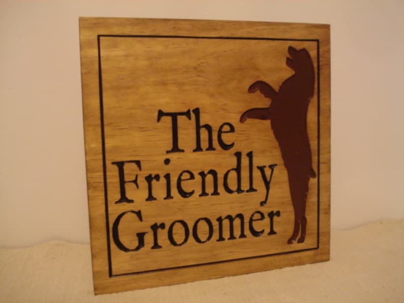 May include: A wooden sign with the text "The Friendly Groomer" and a brown silhouette of a dog standing on its hind legs.