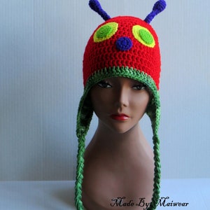 May include: A red, green, yellow, and blue crocheted hat inspired by The Very Hungry Caterpillar book. The hat has a long green braid on each side.