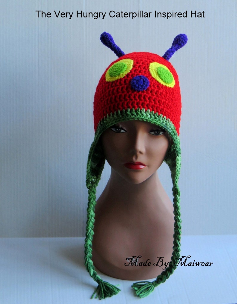 May include: A red, green, yellow, and blue crocheted hat inspired by The Very Hungry Caterpillar book. The hat has a long green braid on each side.