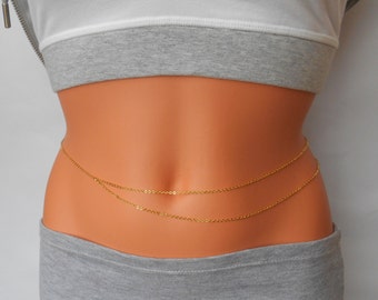 May include: A gold chain body jewelry piece with two strands of chain. The chain is worn around the waist and is a popular accessory for women.