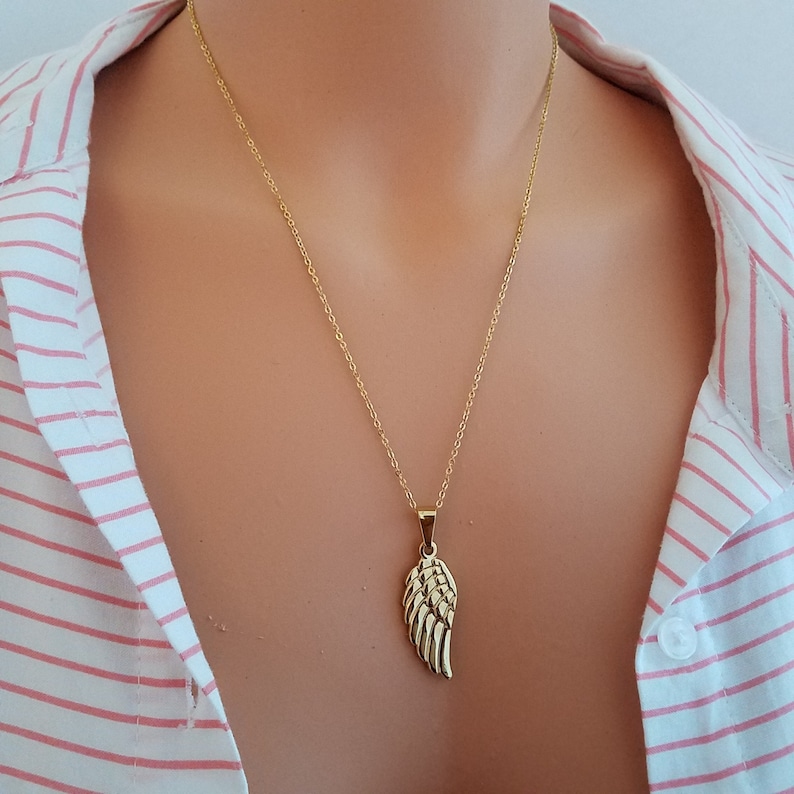Op de afbeelding: Een gouden ketting met een delicate gouden engelenvleugel hanger.