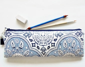 May include: A blue and white patterned pencil case with a zipper closure and a tassel. The case is made of fabric and has a traditional design.
