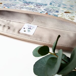 May include: A beige zippered pouch with a white floral print and a white label with the text "GOOD FOR YOU" in black and red lettering.