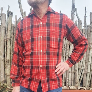 Puede incluir: Una camisa de franela a cuadros rojos y negros con cuello abotonado y mangas largas.