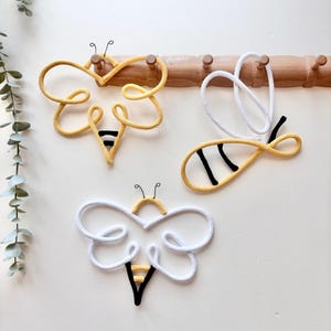 Handmade bumblebee wall decor set displayed on wooden hooks