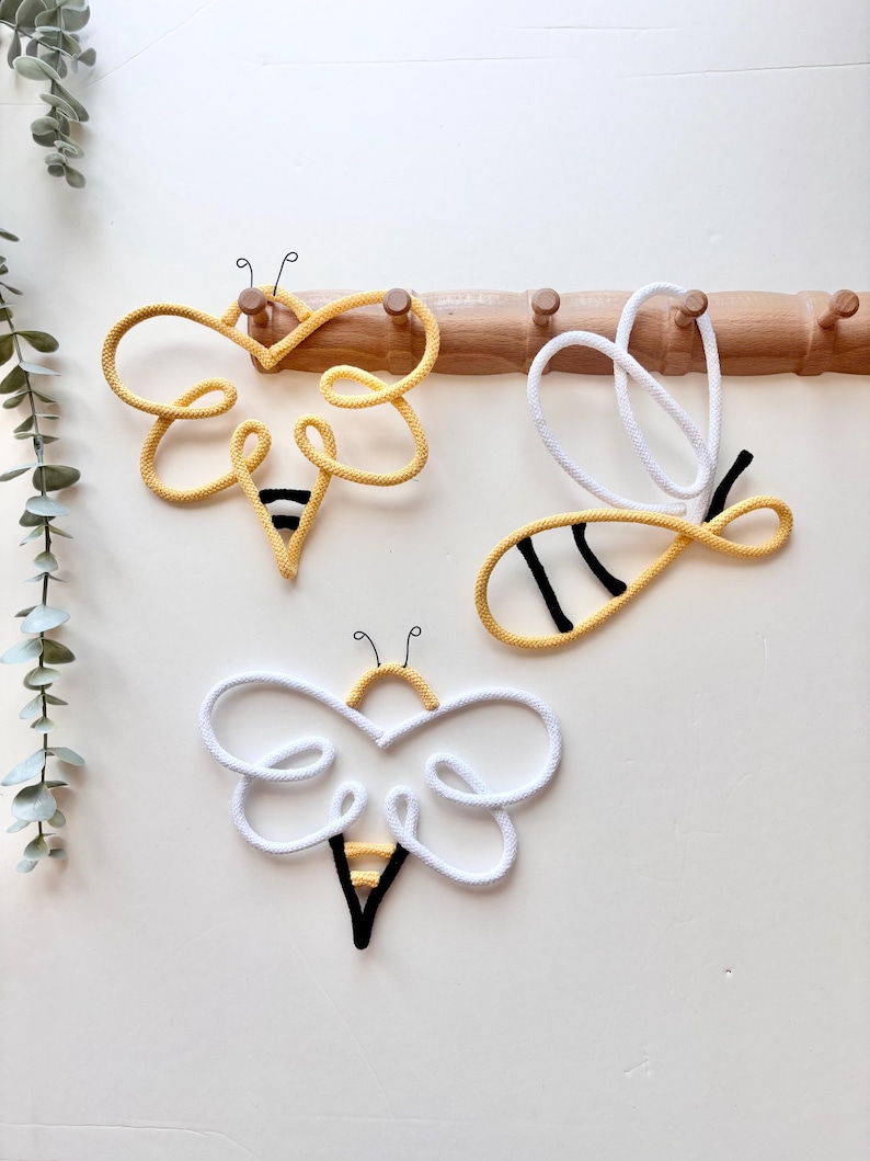 Handmade bumblebee wall decor set displayed on wooden hooks