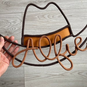 Handmade cowboy hat decor with child's name, perfect for western-themed nursery or kids room.