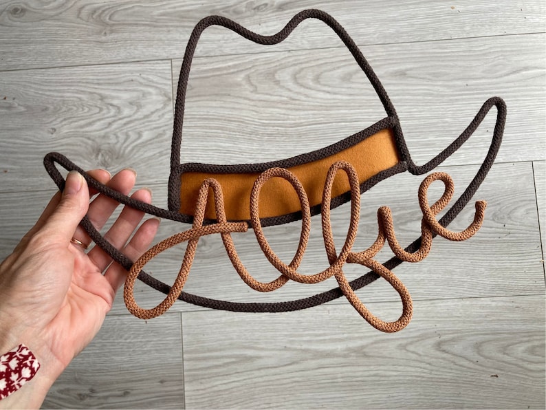 Handmade cowboy hat decor with child's name, perfect for western-themed nursery or kids room.