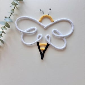 Cute core bee decor styled on wall hooks in light nursery space